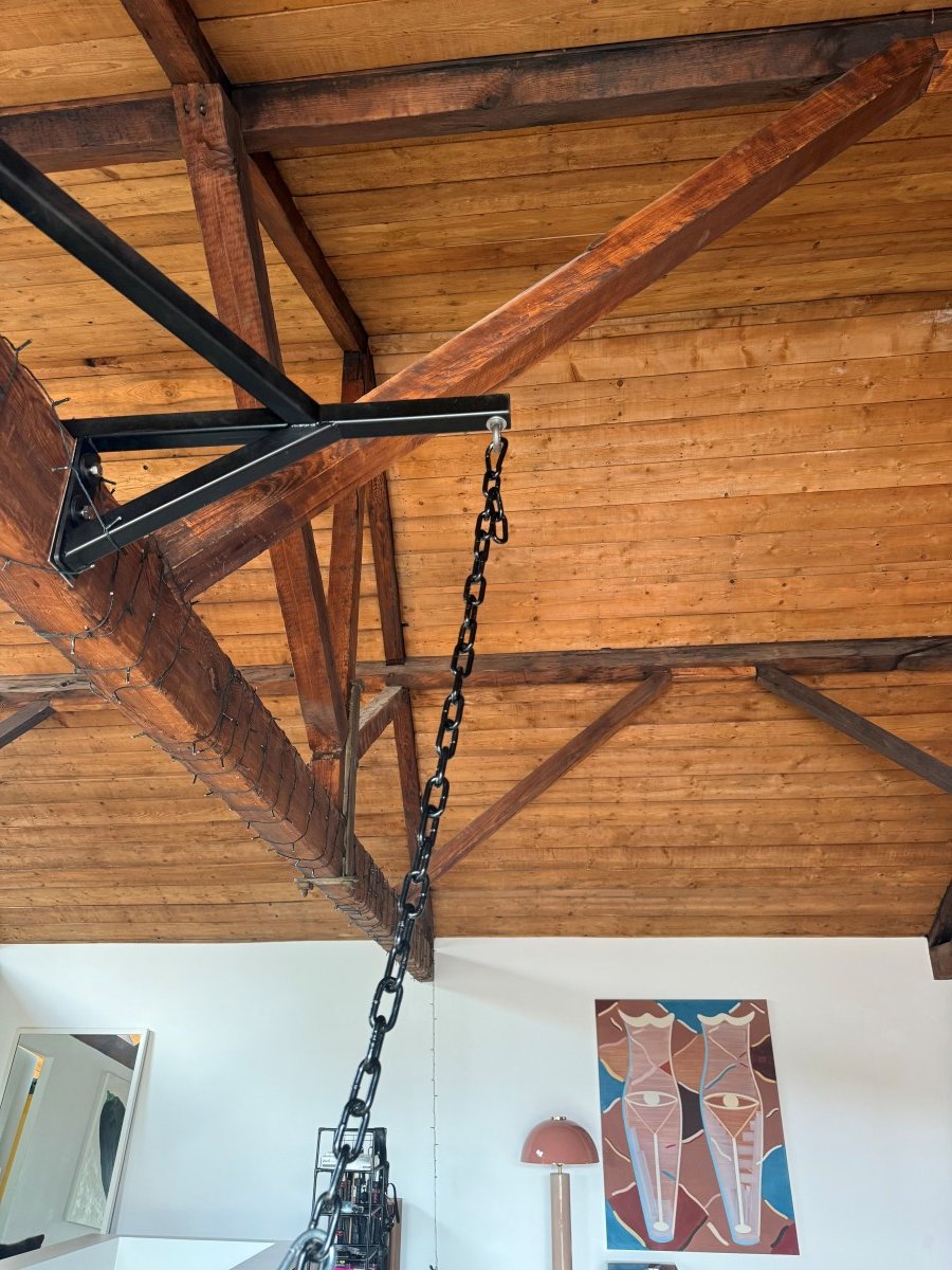 Wooden ceiling with exposed beams and a black metal chain hanging down in a modern loft.